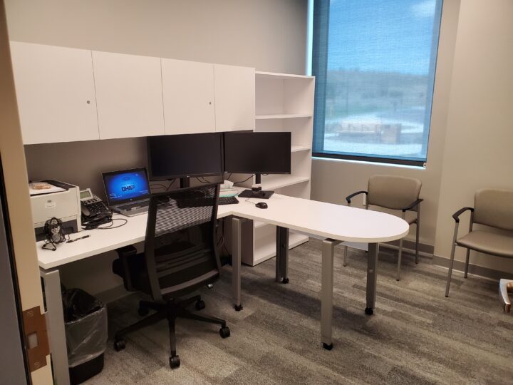 Office with desk,  chair, computer, 2 monitors, phone, and printer. 