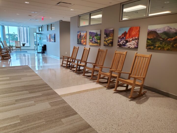 Hallway with wooden rocking chairs and colorful artwork depicting nature.